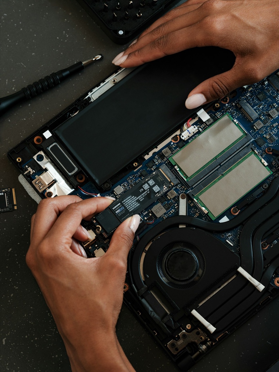 Samsung SSD being installed in a laptop beside its memory modules